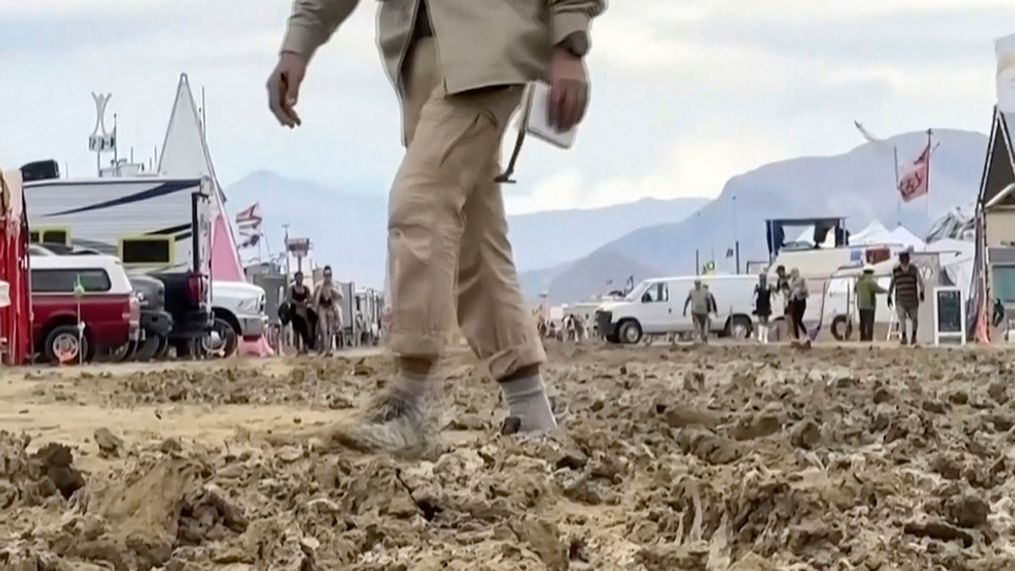 In this image from video provided by Rebecca Barger, a man walks through mud at the Burning Man festival site in Black Rock, Nev., on Monday, Sept. 4, 2023. (Rebecca Barger/@rebeccabargerphoto via AP)